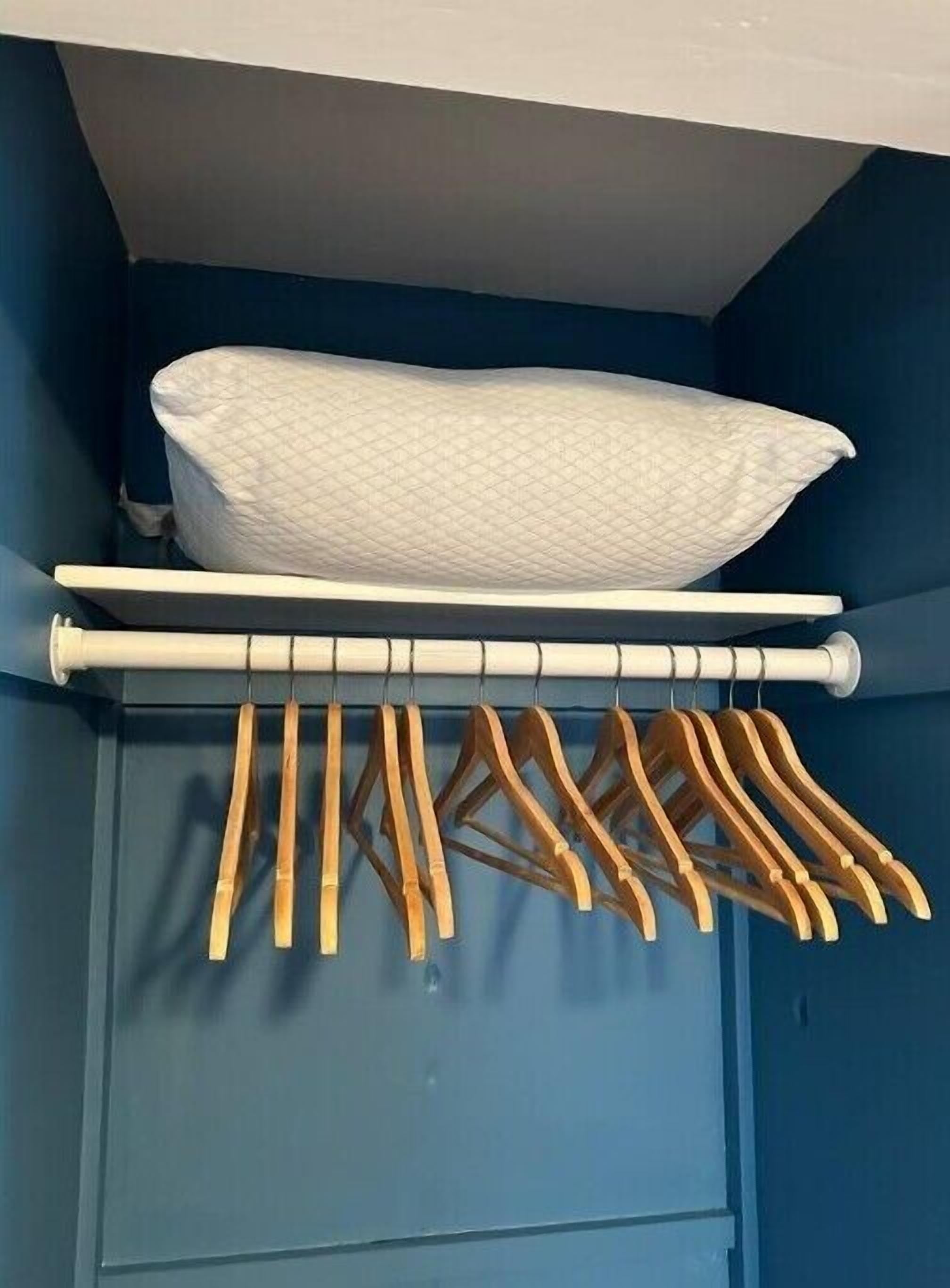 Kaappi, jossa on vaatetanko ja päällä taitettu patja.