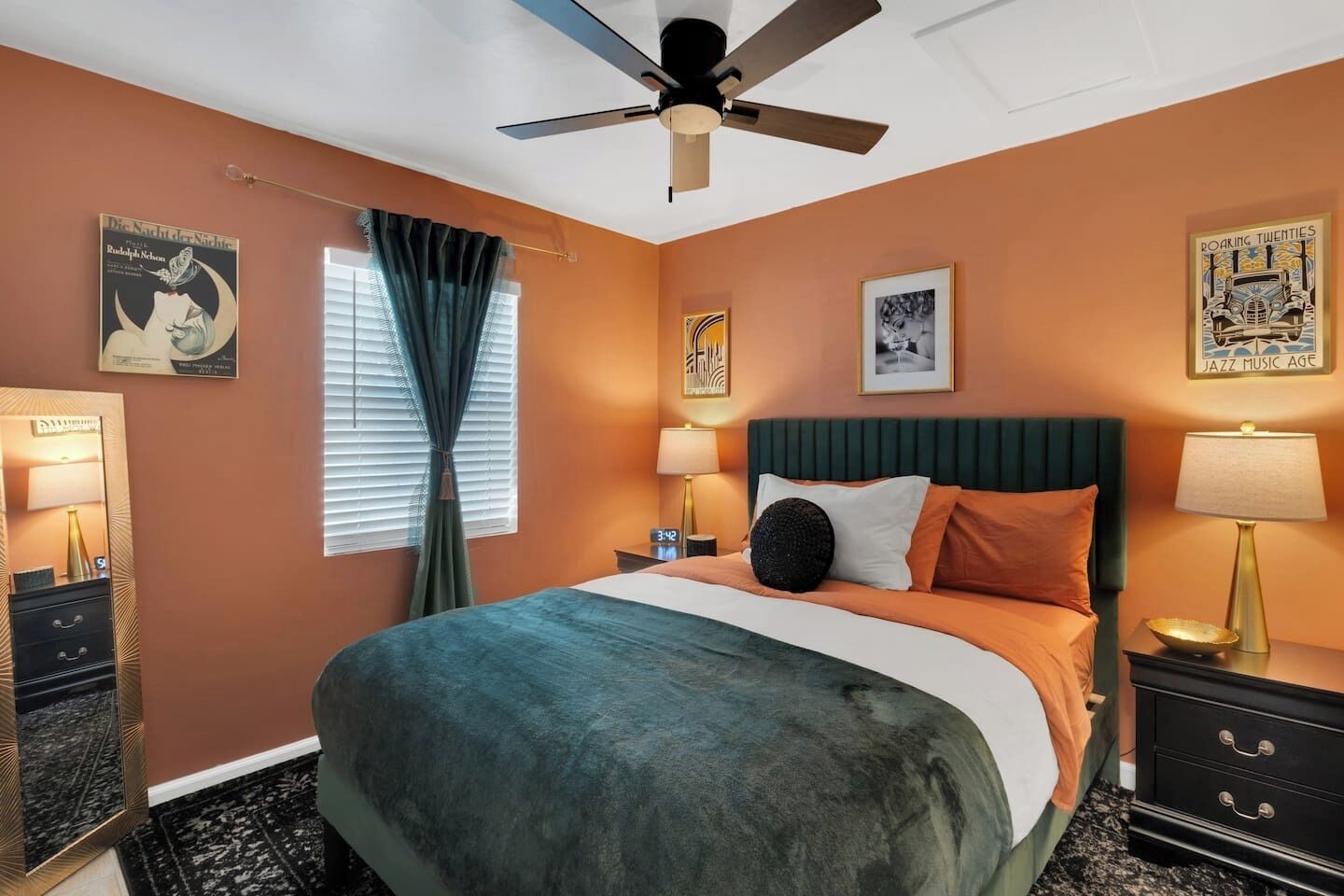 A bedroom with a bed, nightstands, a ceiling fan, and artwork on the walls.