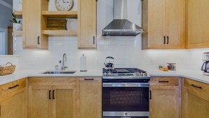A kitchen with wooden cabinets, a stainless steel stove, and a clock on the wall. - Located in Northtown Arcata, The Yellow Doors `A` (Arcata)