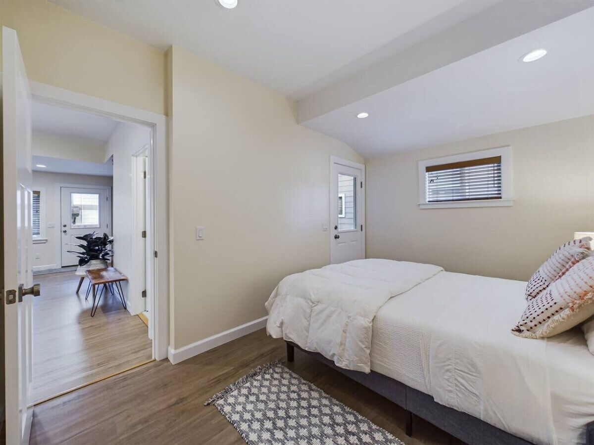Une chambre à coucher avec un lit, une fenêtre et une porte donnant sur une autre pièce.