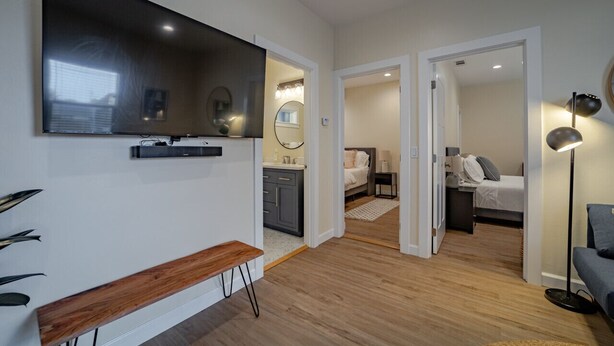 Een moderne hotelkamer met een grote flatscreen televisie, een bankje, een bureau, een bed en een nachtkastje.