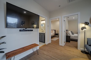 A modern hotel room with a large flat-screen TV, a bench, a desk, a bed, and a bedside table. - The Yellow Doors `B` (Arcata)