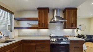 Een moderne keuken met houten kastjes, een roestvrijstalen fornuis en een inbouwafzuigkap.