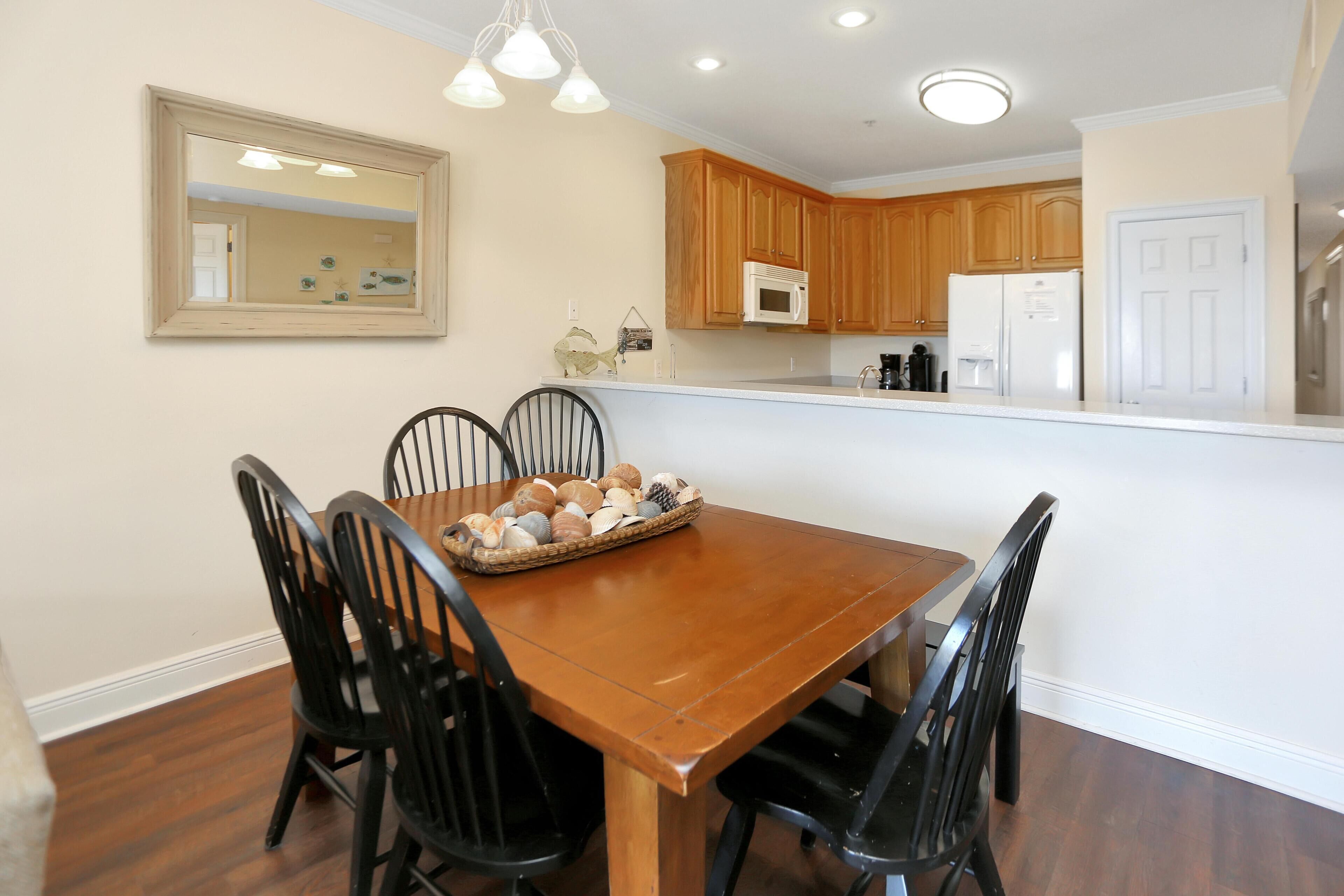 A dining area with a wooden table and black chairs, a basket of bread, and wooden cabinets in the background.