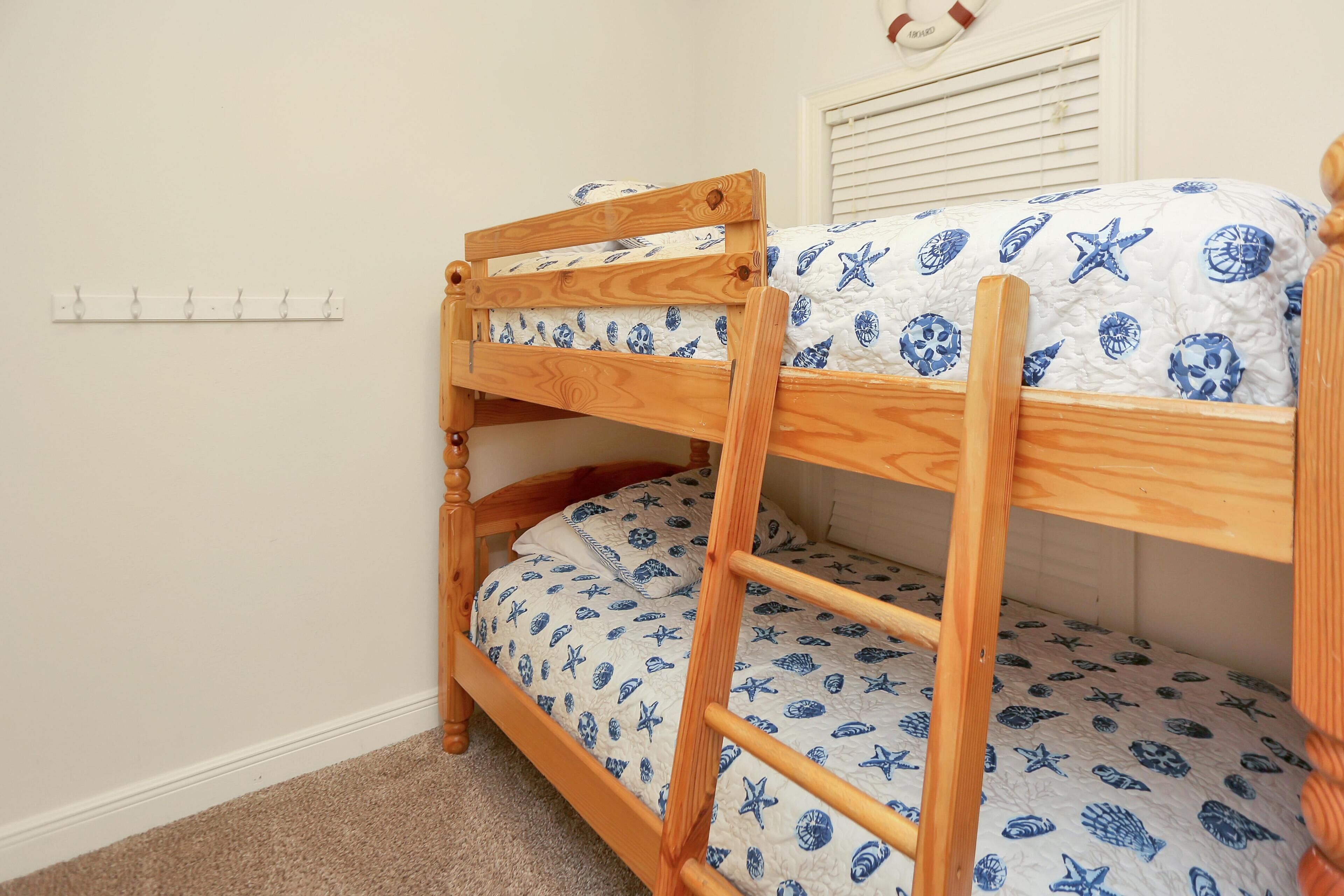 A bunk bed with a wooden frame and a blue and white patterned bedspread.
