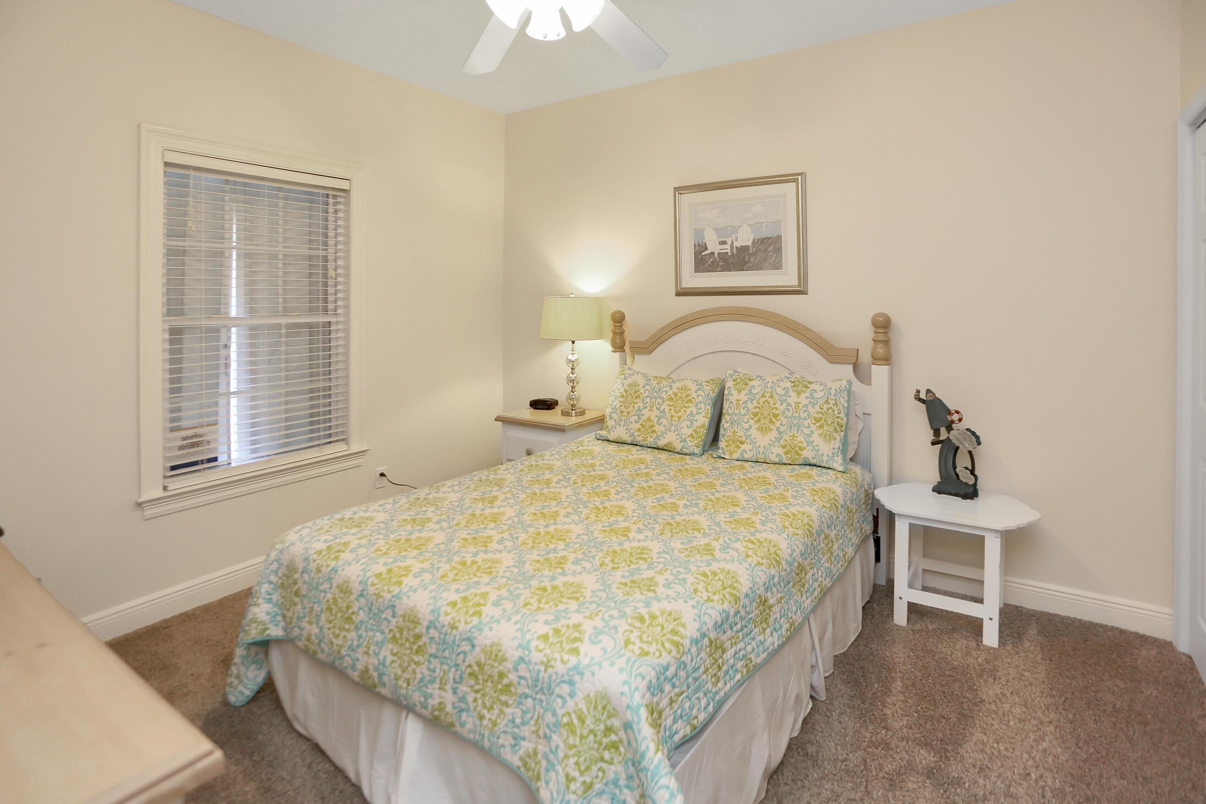 A bedroom with a bed, bedside table, lamp, and a framed picture on the wall.