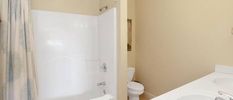 A bathroom with a bathtub, toilet, and two sinks.