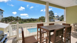 A covered outdoor area with a pool, wooden furniture, and a view of the surrounding landscape. - Dunes Club 1B (Port St. Joe)