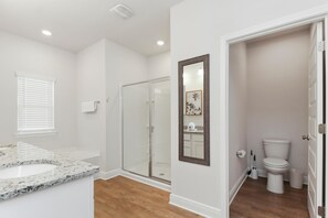 Bathroom features a glass-enclosed shower, white sink, and large mirror.