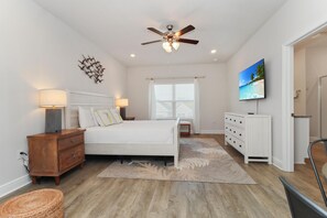 Cozy retreat with a large bed, nightstand, and dresser, plus a TV and ceiling fan.