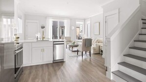 Una cocina moderna con muebles blancos, lavavajillas y un comedor con mesa y sillas.