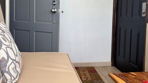 A room with a bed, a door, and a small wooden table. - Charming tropical beach retreat Suite 1 (Hellshire)