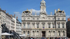 Ein historisches Gebäude mit klassischer Architektur, mit einem markanten Glockenturm und Statuen.