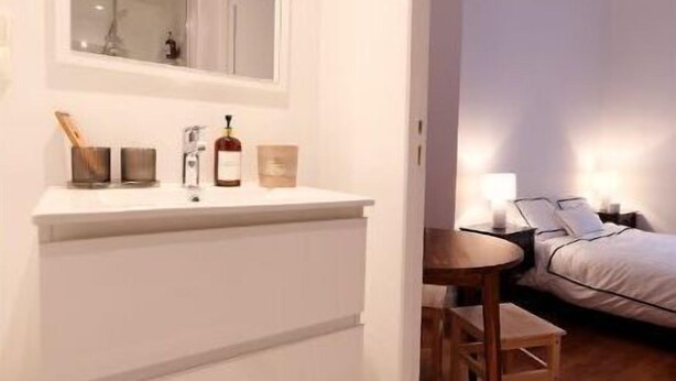 Ein modernes Badezimmer mit einem großen Spiegel, einem weißen Waschtisch und einem Holzboden.