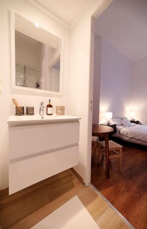 Une salle de bain moderne avec un grand miroir, un meuble-lavabo blanc et un plancher en bois.