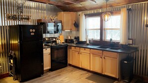 Una cocina con armarios de madera, un refrigerador negro, una estufa y un lavamanos.