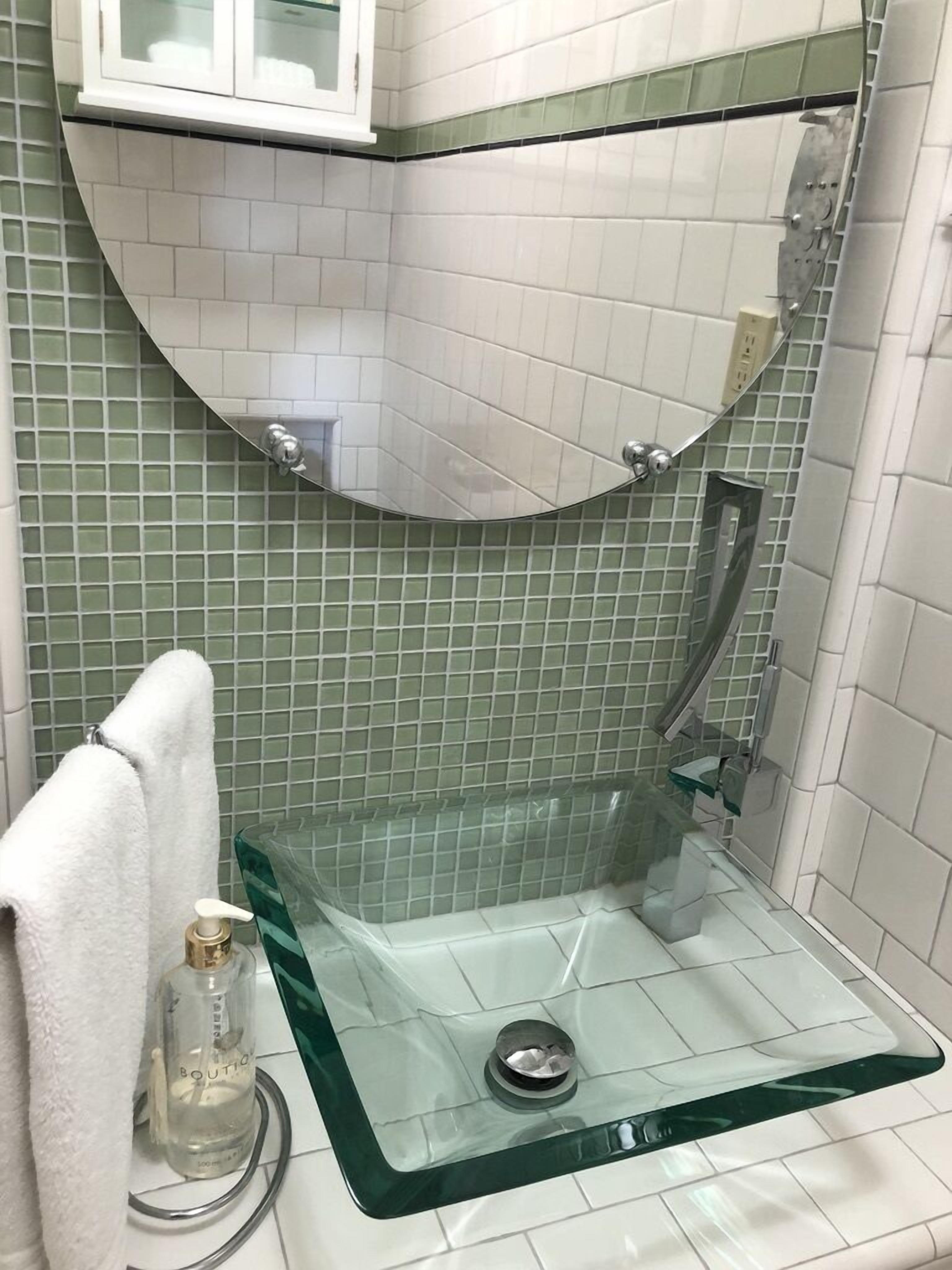 Un baño con cabina de ducha de vidrio, una toalla blanca y una botella de loción.