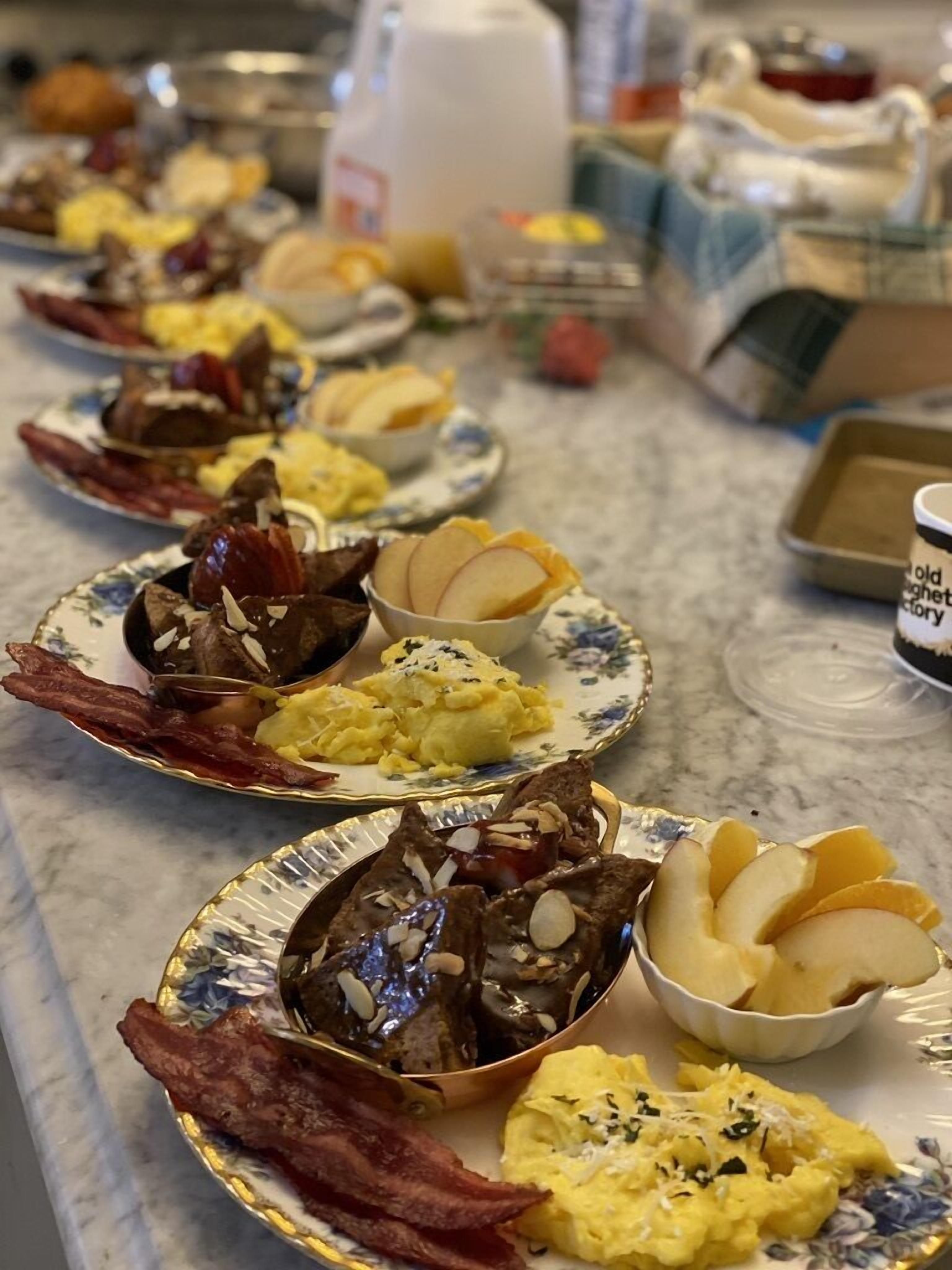 A breakfast buffet with various dishes including scrambled eggs, bacon, and fruit.