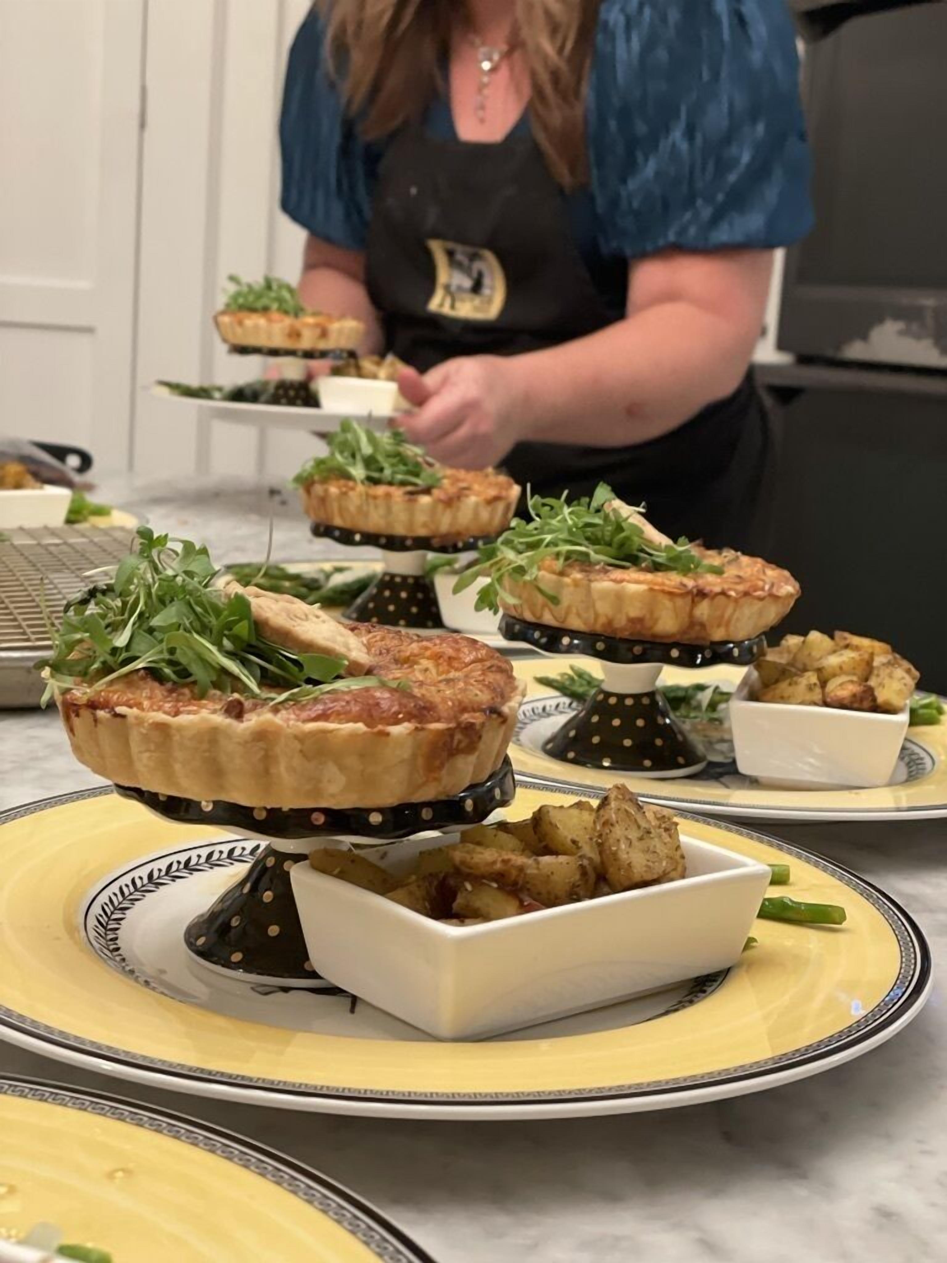 A kitchen with multiple dishes of food, including quiches and roasted potatoes, on a marble countertop.