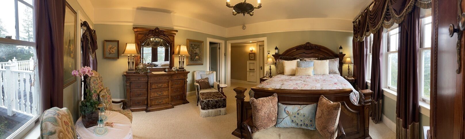 A bedroom with a large bed, a dresser, a vanity, and a chair.