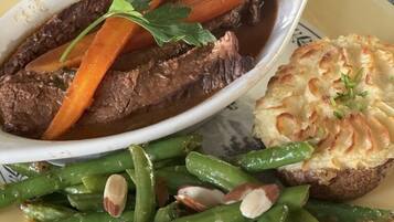 A plate with beef, carrots, green beans, and a baked potato.