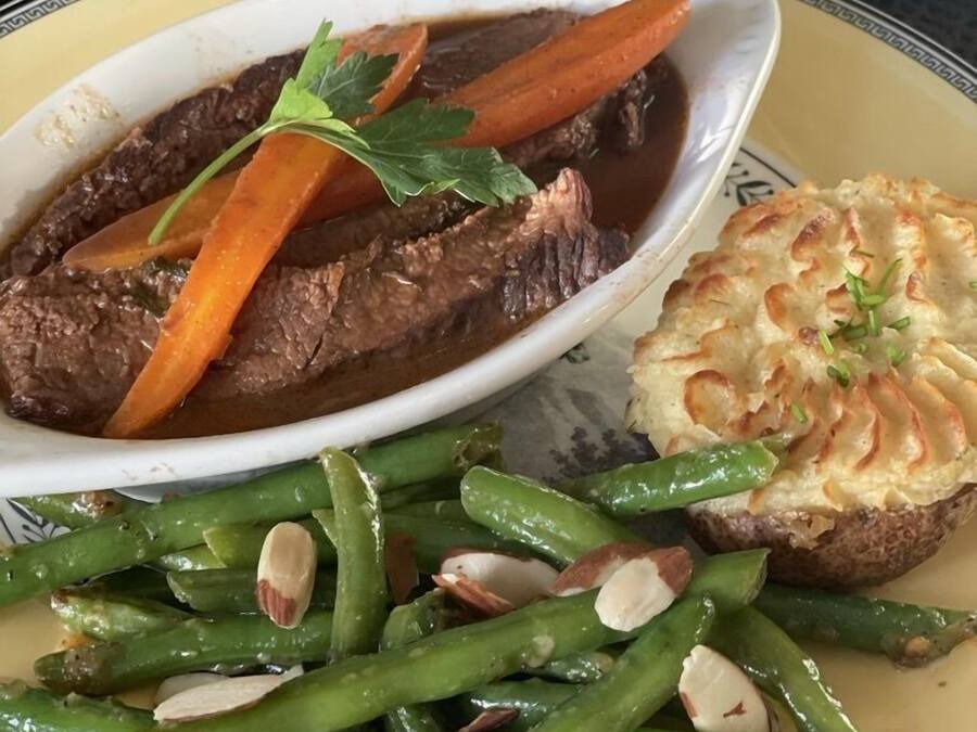 A plate with beef, carrots, green beans, and a baked potato.