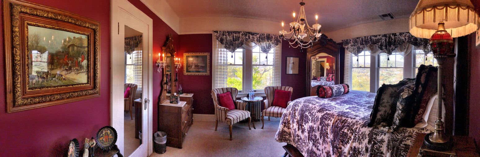 A room with a large bed, a chandelier, and a window with a view.