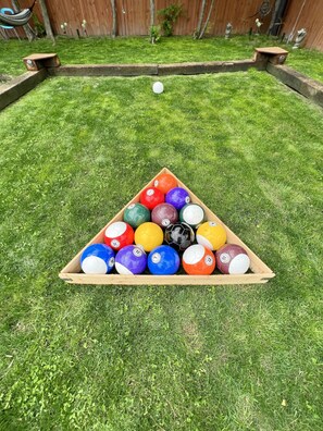 Een houten, driehoekig bord vol met kleurrijke voetbaltjes op een gazon.