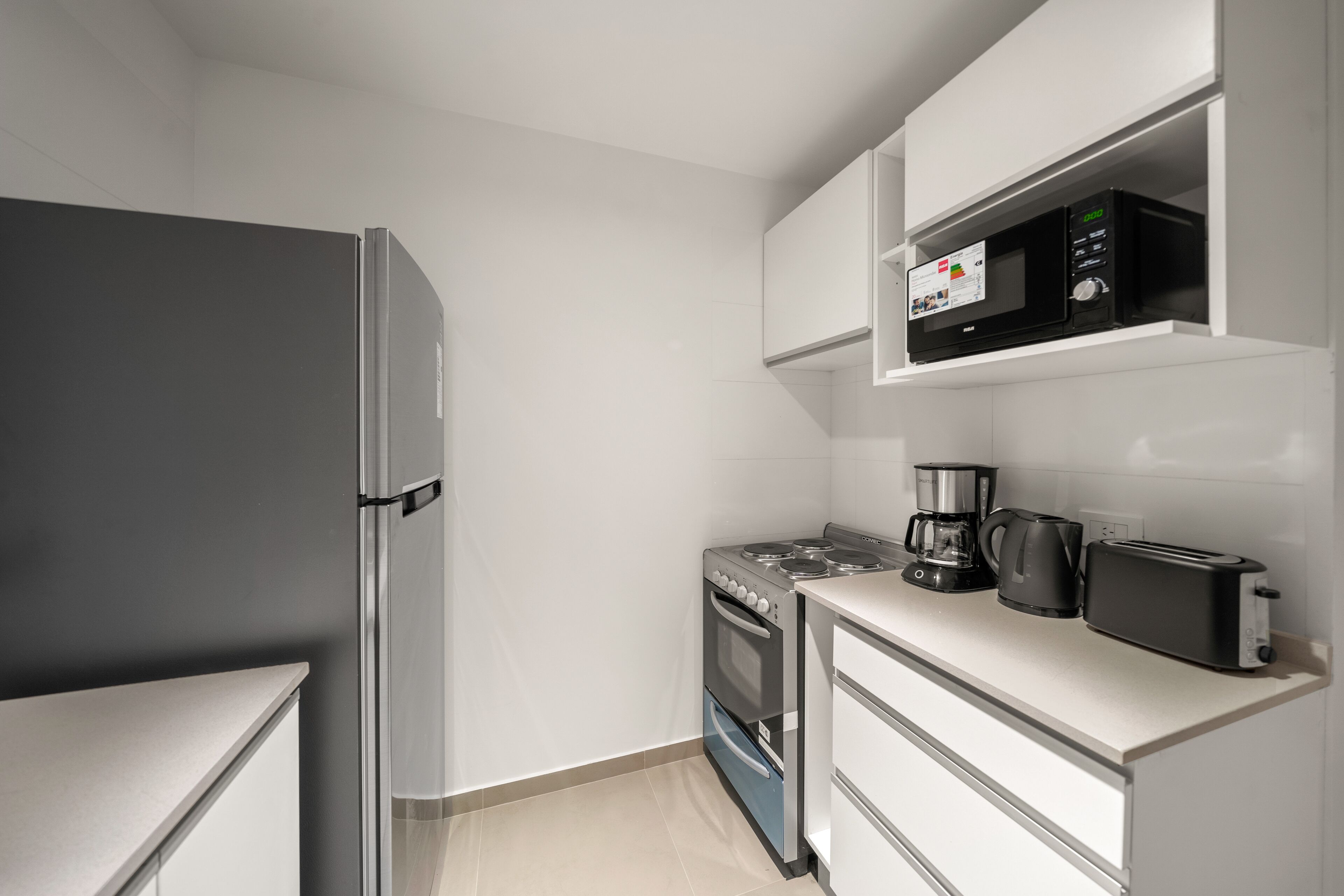 A compact kitchen with a refrigerator, stove, microwave, coffee maker, and toaster.