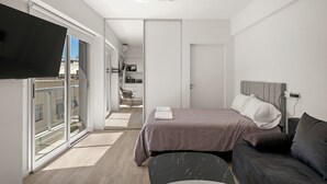Un dormitorio moderno con cama, sofá y televisor.