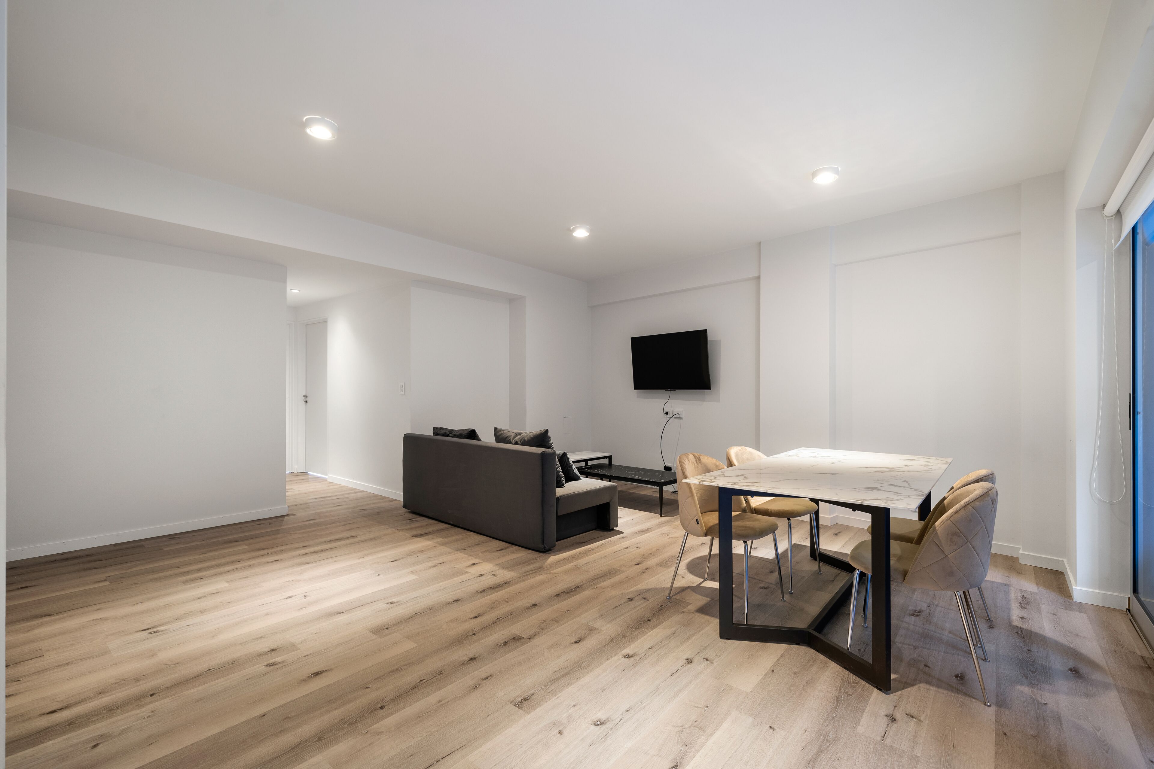 A modern, minimalist living room with a sofa, dining table, and chairs.