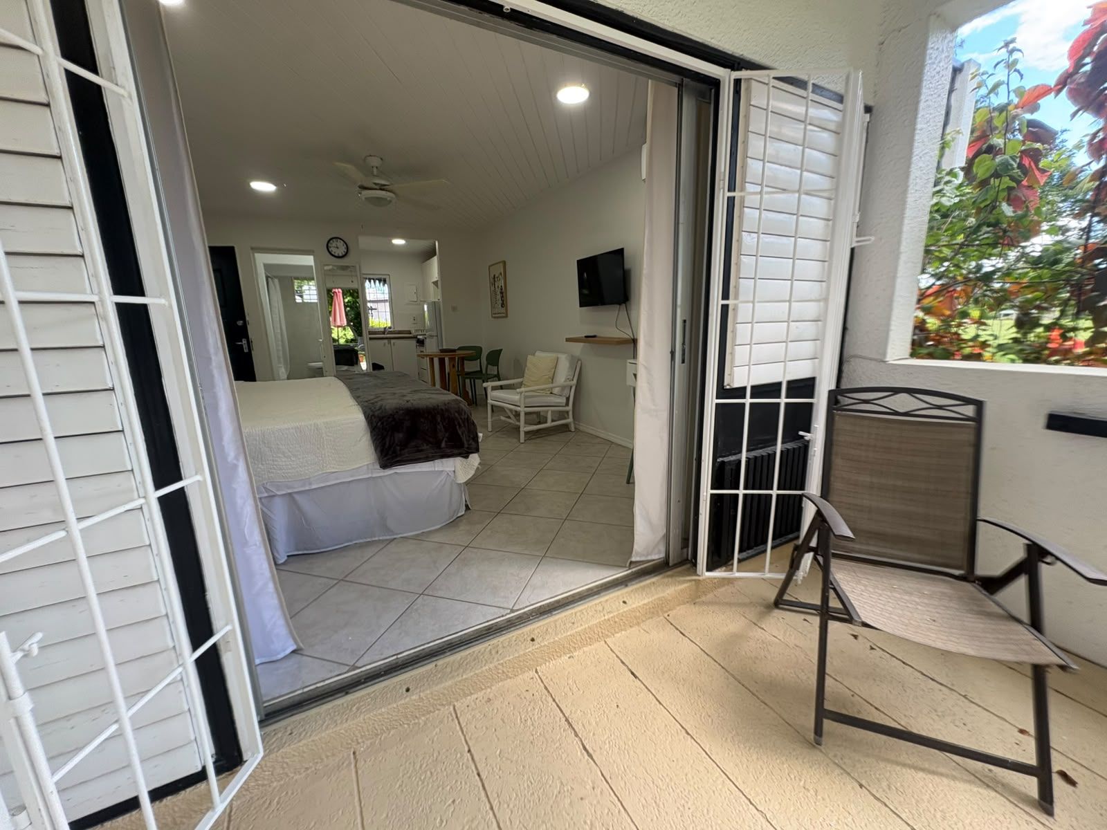 Ein Zimmer mit einem Bett, einem Sessel, einem Fernseher und einem Fenster mit Jalousien.