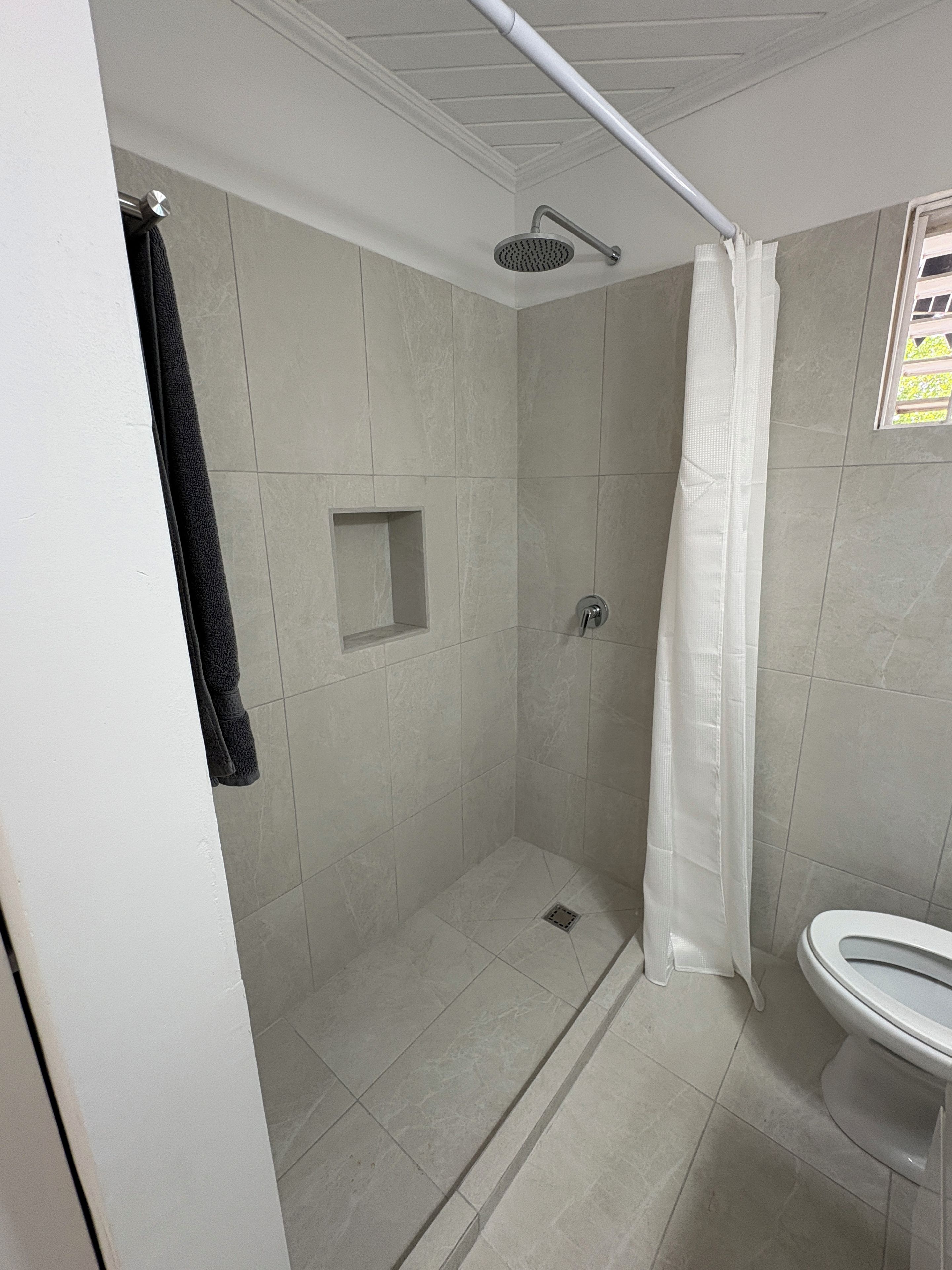 A bathroom with a shower, toilet, and a towel rack.