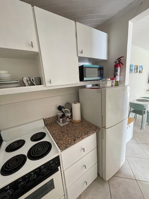 A kitchen with white cabinets, a microwave, a stove, and a refrigerator.