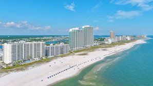 Um hotel costeiro com vários edifícios altos, uma extensa faixa de areia e um céu azul límpido.