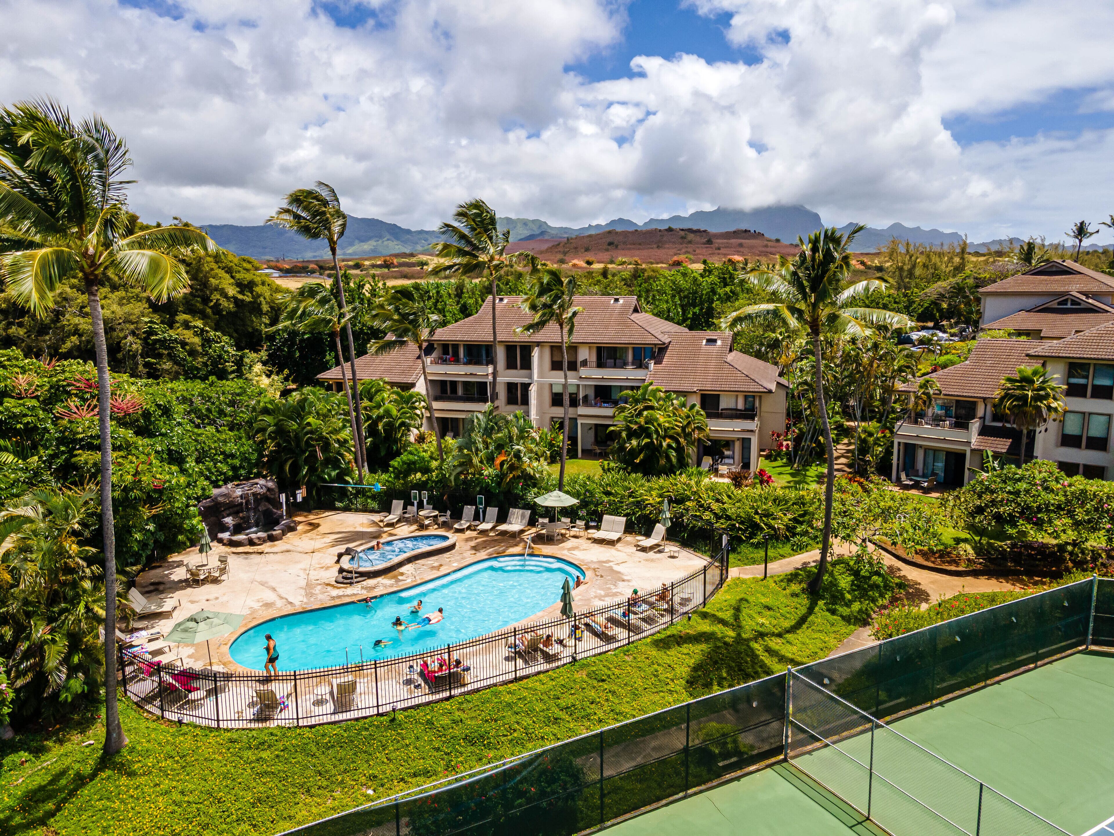 A resort with a swimming pool, lounge chairs, and a view of mountains.