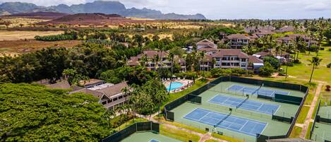 Un resort con varias canchas de tenis, una piscina y vistas a la montaña.