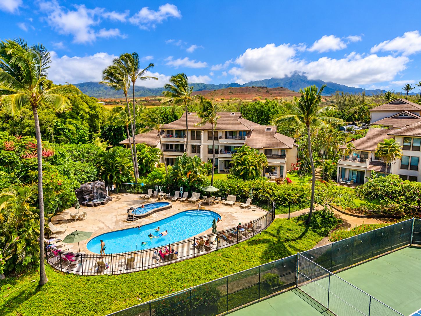 A resort with a swimming pool, lounge chairs, and a view of mountains.