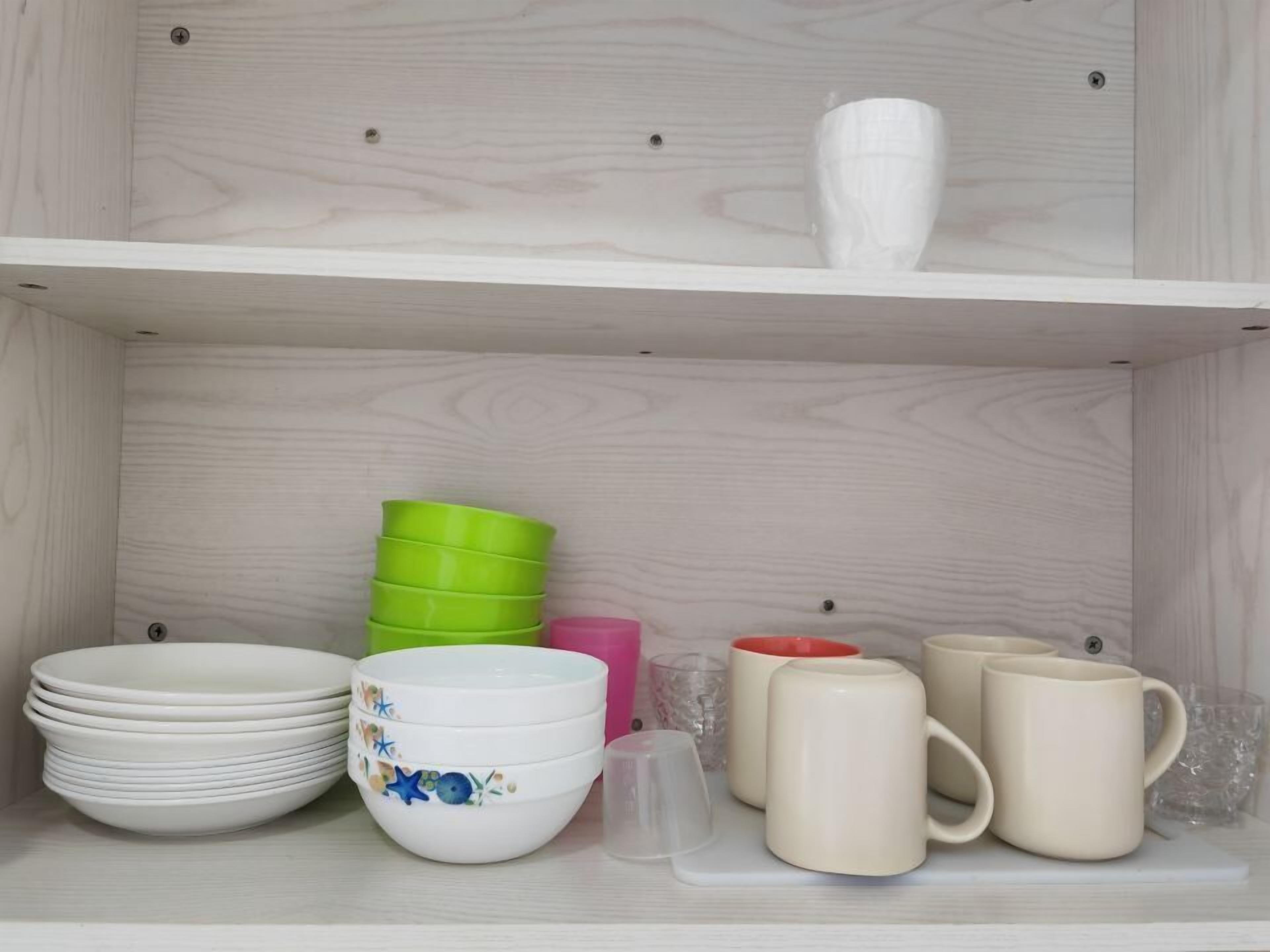 A shelf with white plates, bowls, and mugs.