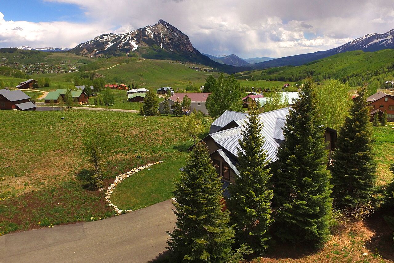 A rural village with houses, a winding road, and mountains in the background.