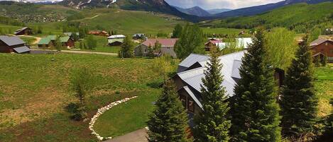 A rural village with houses, a winding road, and mountains in the background.