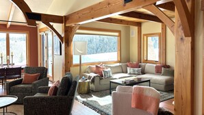 Un salon chaleureux avec un plafond en bois, de grandes fenêtres, un canapé, un fauteuil et une table basse.