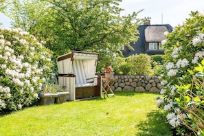Een tuin met een rieten stoel en een stenen muur.