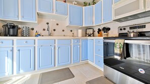A kitchen with blue cabinets, a microwave, a stove, and various kitchen utensils. - ᨒ Hot Tub / Fire Pit / Game Lounge / Fenced Yard ᨒ (Colorado Springs)