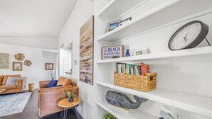 Een moderne woonkamer met een bank, een salontafel en een boekenkast vol decoratieve objecten en boeken.