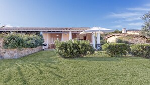 A house with a covered patio, a lawn, and a stone wall. - Casa Cactus Seaview with Pool (Tertenia)