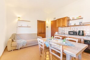 A compact living space with a kitchenette, a dining table, and a sofa.