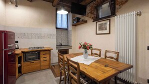 A compact kitchen with a built-in oven, a red refrigerator, and a wooden dining table with chairs. - Holiday apartment in a sunny location (Madonna Del Sasso)