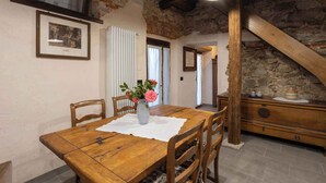 A rustic dining area with a wooden table, chairs, and a vase of flowers. - Holiday apartment in a sunny location (Madonna Del Sasso)