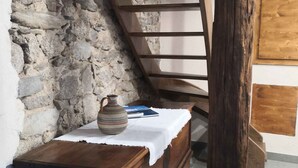 A rustic room with a wooden chest of drawers, a stone wall, and a wooden ladder. - Holiday apartment in a sunny location (Madonna Del Sasso)